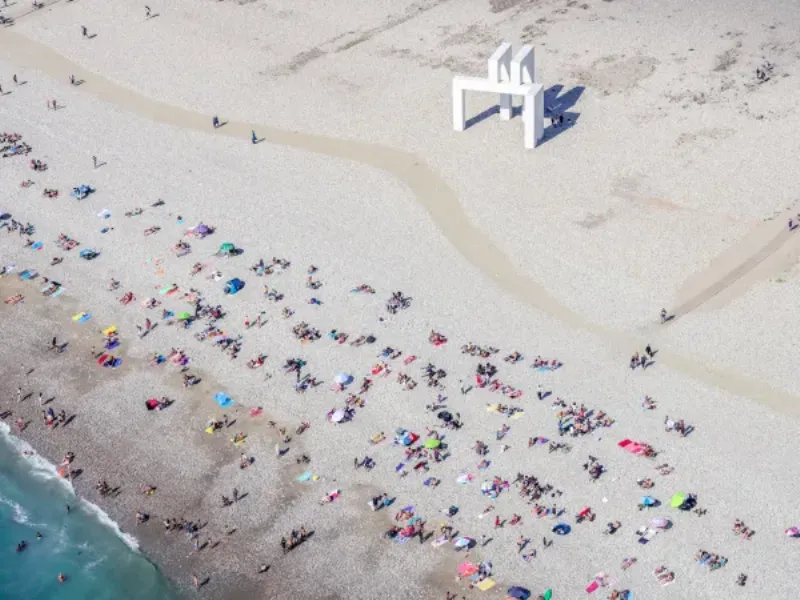 Une sculpture totem contemporaine et monumentale en métal, colorée, installée dans un parc urbain moderne en France.